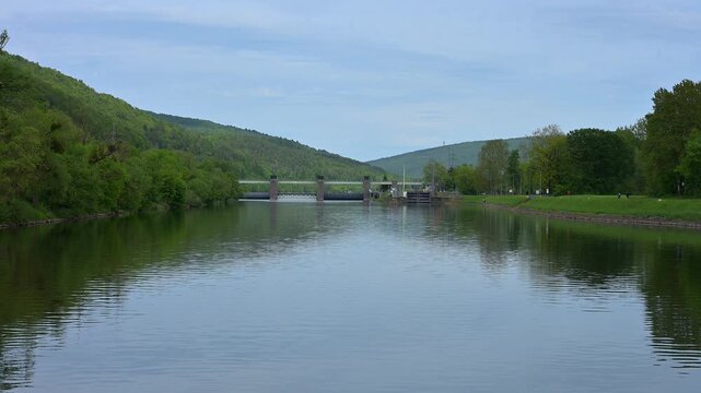 Fluss mit Staumauer und gr&uuml;nen H&uuml;geln, unter klarem Himmel, Main, Wasserkraftwerk Steinbach, Lohr am Main, Landkreis Main-Spessart, Spessart, Mainfranken, Unterfranken, Bayern, Deutschland