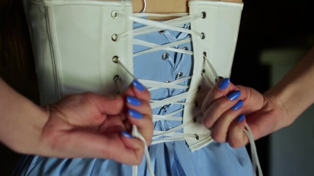 Hands tightening the laces of a corset on the back