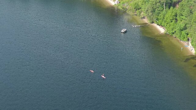 Aerial view of Stand Up Paddle Board and kayak paddling on lake on summer afternoon