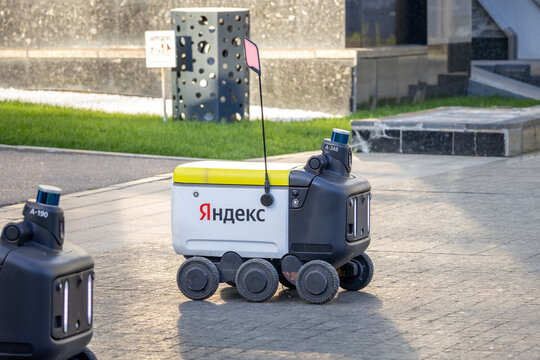 Yandex delivery robot in a square, waiting for a task. Another robot is partially visible in the foreground. Moscow, Russia - June 22, 2024