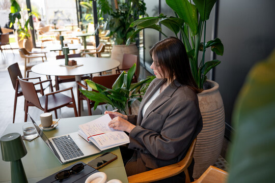 Businesswoman multitasking in a modern cafe workspace