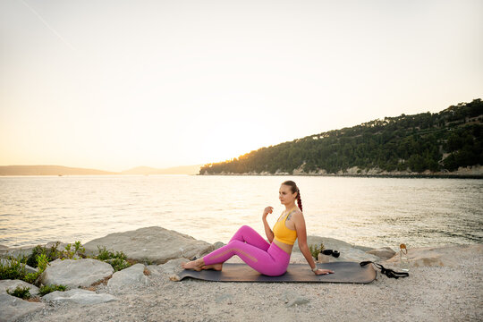 Woman practicing yoga by the sea at sunset for balance