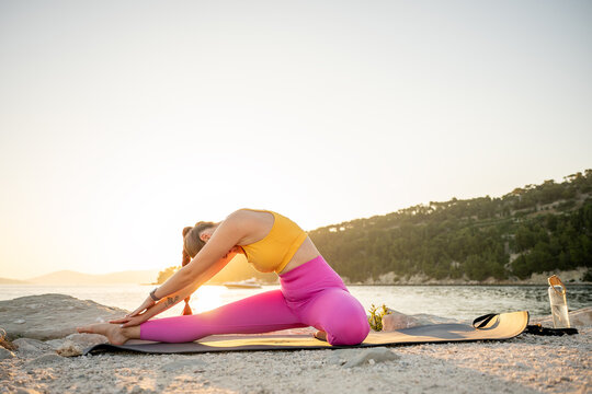 Woman practicing seaside yoga stretch at sunrise for balance