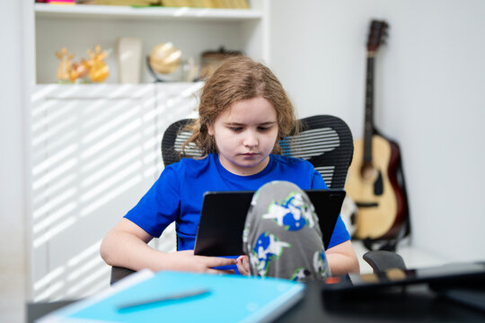 Child using laptop at home school. Kid studying online at desk with laptop. Kid online lesson on laptop. Teenager doing homework on laptop.
