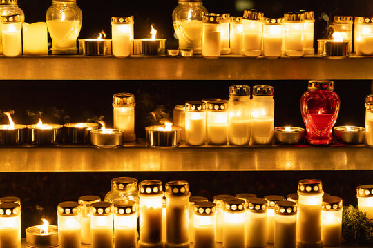 Memorial candles glowing at night in a cemetery setting