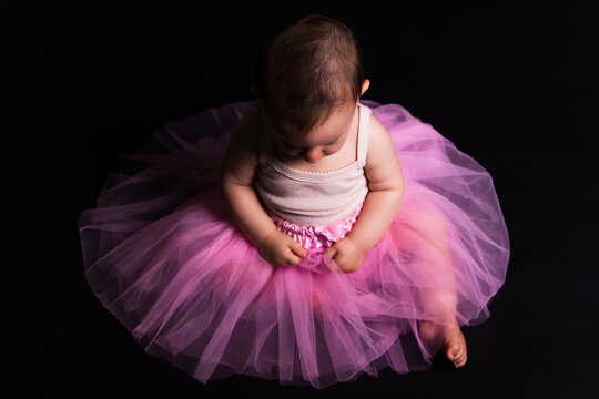 Baby girl wearing a pink tutu on a black background