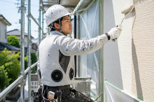 空調服を着ながら外壁を塗装する職人
