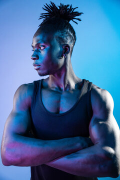 Muscular African man in neon light with crossed arms