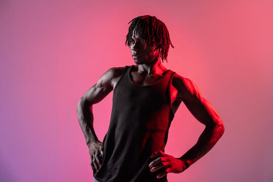 African man in black tank top under red studio light