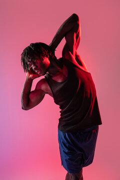 African man stretching in dramatic red studio light