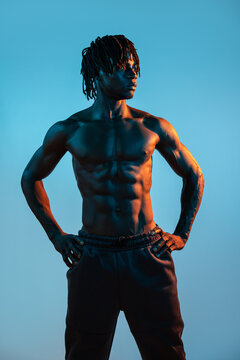 Muscular African man pose shirtless in dramatic blue light