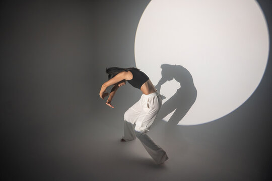 Latin urban dancer pose before circular spotlight and shadow