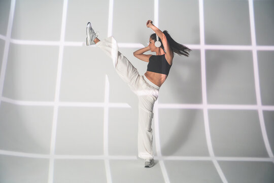 Latin woman perform high kick in urban dance studio