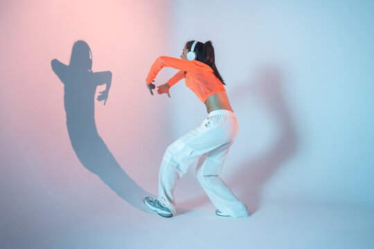Latin woman dance with headphones and dramatic shadow