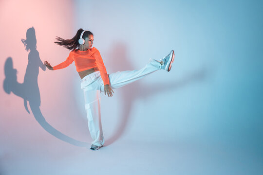 Latin urban dancer in headphones performing high kick