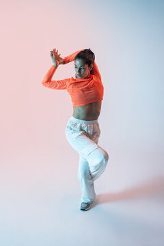 Latin woman performing urban dance in colorful studio light