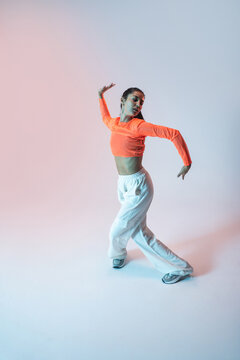 Latin woman perform urban dance in colorful studio light