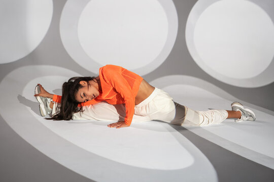 Latin woman urban dancer performing floor split in studio