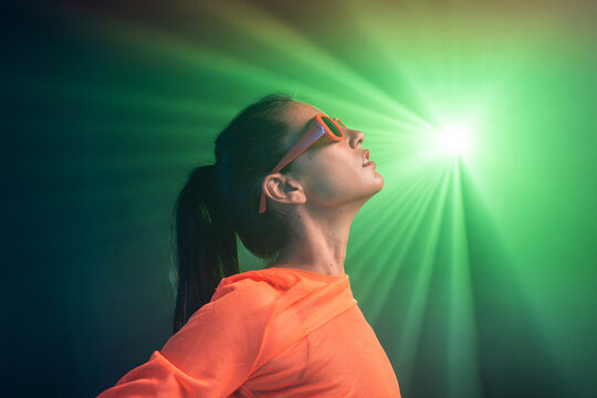 Latin woman in orange activewear under green stage light