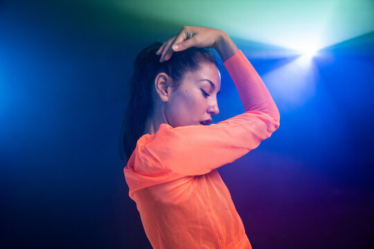 Latin urban dancer pose under colorful stage light