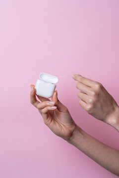 Caucasian woman hands using dental floss on pink background