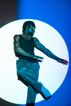 African man dancing in neon light with circular backdrop