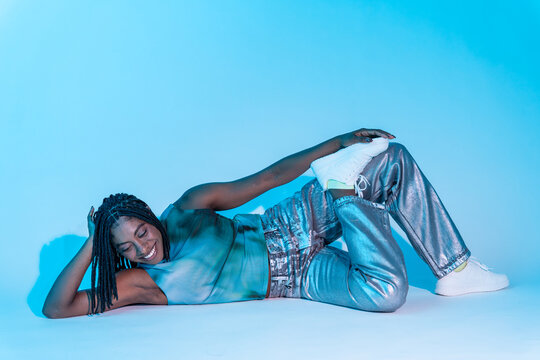 Afro woman dancer posing in blue studio with neon mood