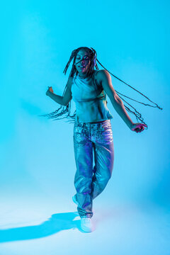 Afro woman dancer moving in blue neon studio light
