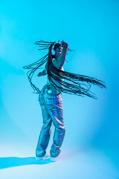 Afro woman dancer moving in neon light with headphone and braids