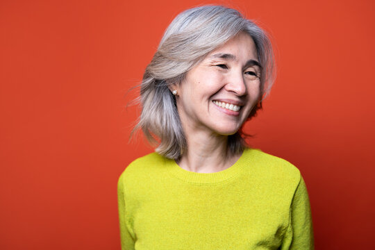 Smiling senior Asian woman portrait on orange background