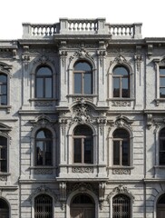 Obraz premium Ornate building facade with arched windows and decorative stone carvings. Classic architecture exterior detail shows historical stonework and window frames in an old city street.