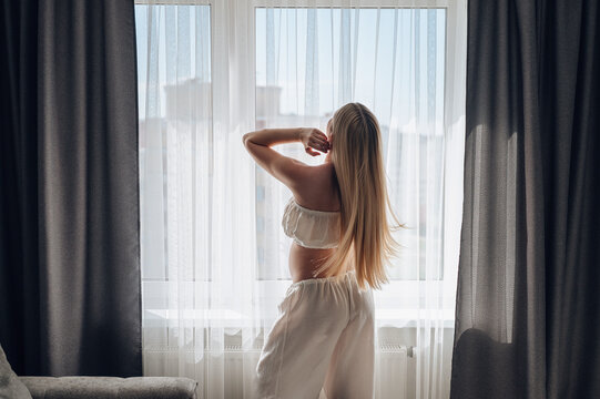 Pregnant woman by window in cozy home morning light