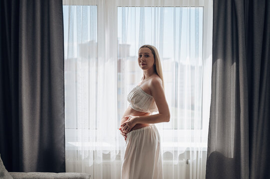 Pregnant woman by window in cozy home lifestyle scene