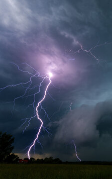 Vertical view of a powerful lightning strike bolts flashing down to the ground during a severe night thunderstorm