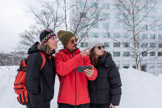 Friends using smartphone at Japan ski resort in snowfall