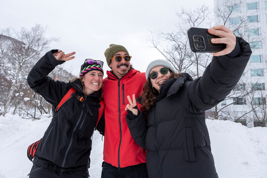 Friends taking a smartphone selfie in snowy Japan ski resort