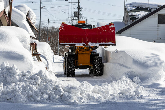 Red Snowplow Clearing Deep Snow on A Niseko Street