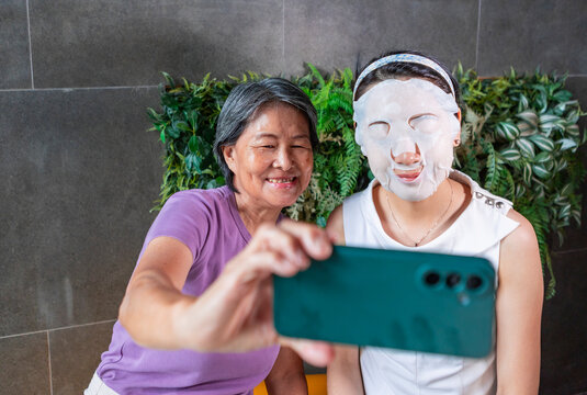 Senior woman and daughter taking selfie with face mask