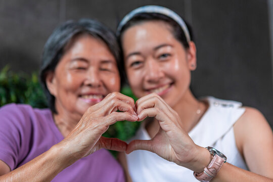 Smiling mother and daughter making heart gesture together