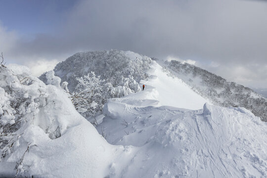 Lone splitboard hiker on snowy ridge in Japan mountains