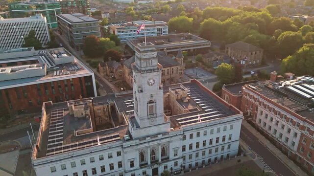Aerial orbit of Union Jack flag on Barnsley Town Hall clock tower at golden hour.