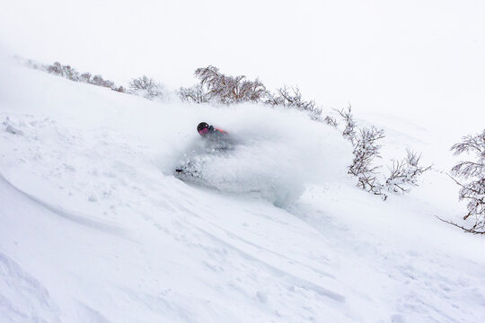 Snowboarder carving through fresh powder in Hokkaido