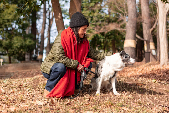 Woman petting her dog on leash during a winter park walk