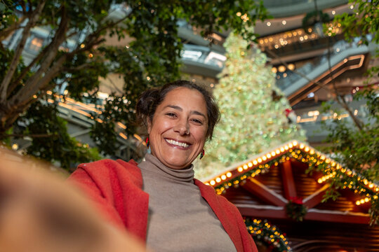 Smiling woman in mall with Christmas tree and lights