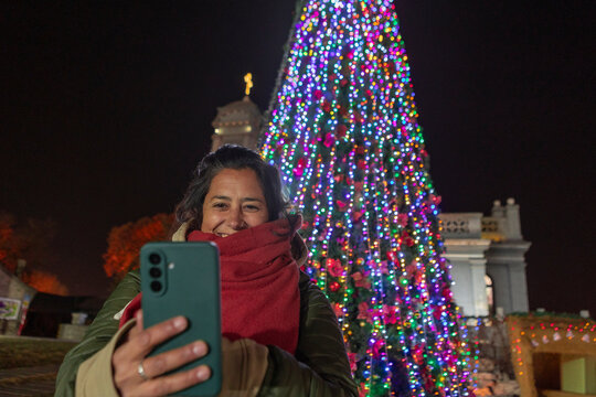 Woman taking selfie by Christmas tree at night in China