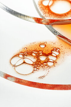 Macro of amber oil bubbles on glass with clean white background