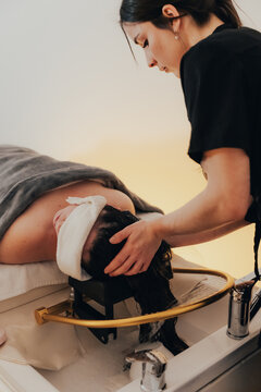 Spa therapist giving relaxing hair wash treatment at sink