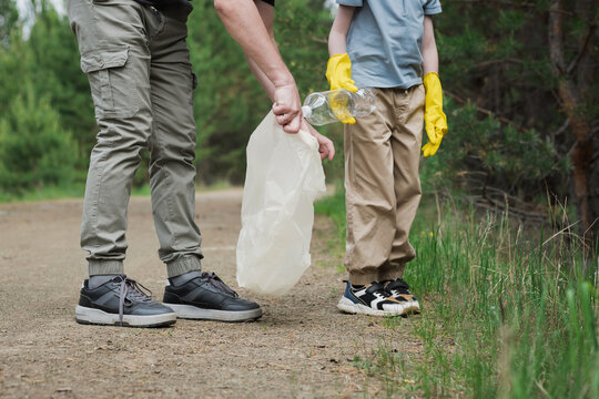 Forest cleanup with adult and child collecting plastic trash