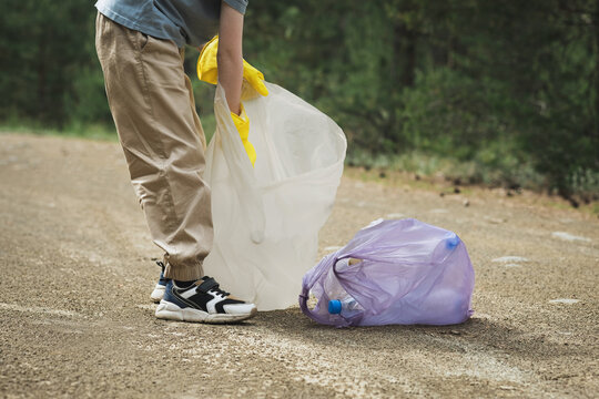 Volunteer picking up plastic garbage on a forest trail