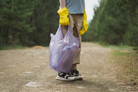 Volunteer holding plastic bag of litter on forest trail